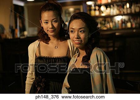 Stock Photograph - Portrait of a young woman smiling with her friend in a nightclub. Fotosearch