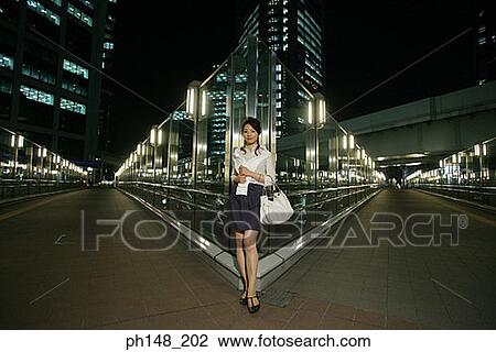 Stock Image - Portrait of a young woman standing on the road. Fotosearch