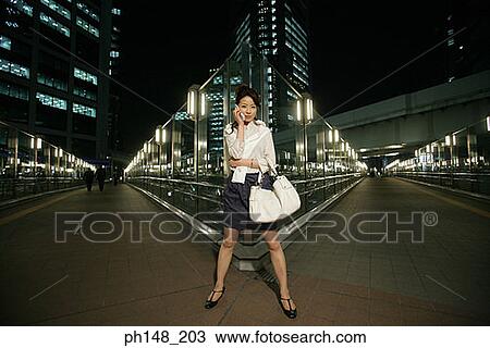 Portrait of a young woman standing on the road and talking on a mobile phone View Large Photo Image Stock Image - Portrait of a young woman standing on the road and talking on a mobile phone. Fotosearch