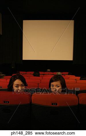 Stock Photography - Portrait of two young women sitting in a movie theater. Fotosearch
