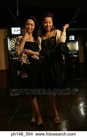 Picture - Portrait of two young women smiling in a nightclub. Fotosearch