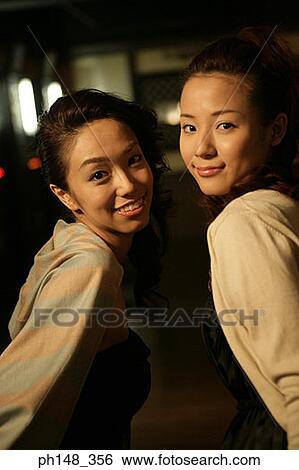Stock Photograph - Portrait of two young women smiling in a nightclub. Fotosearch