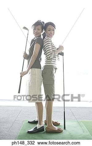 Portrait of two young women standing back to back and holding golf clubs View Large Photo Image Stock Image - Portrait of two young women standing back to back and holding golf clubs. Fotosearch