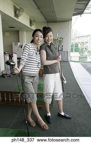 Stock Photo - Portrait of two young women standing and holding golf clubs. Fotosearch