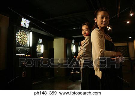 Portrait of two young women standing back to back and smiling in a nightclub View Large Photo Image Stock Photo - Portrait of two young women standing back to back and smiling in a nightclub. Fotosearch