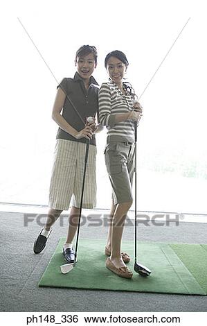 Portrait of two young women standing and holding golf clubs View Large Photo Image Stock Photograph - Portrait of two young women standing and holding golf clubs. Fotosearch