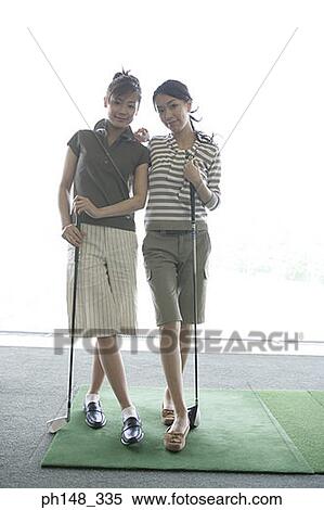 Portrait of two young women standing and holding golf clubs View Large Photo Image Stock Photography - Portrait of two young women standing and holding golf clubs. Fotosearch