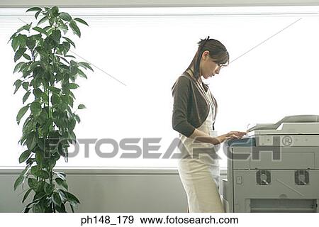 Stock Photo - Side profile of a businesswoman using a photocopier. Fotosearch