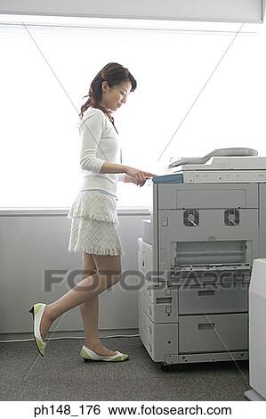 Stock Photograph - Side profile of a businesswoman using a photocopier. Fotosearch