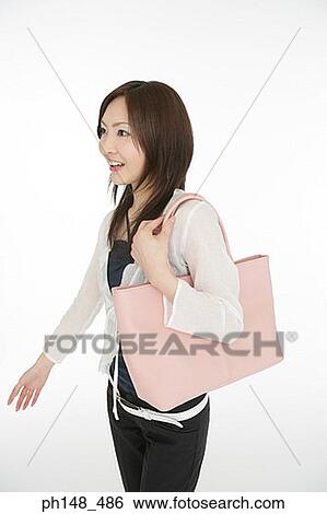 Side profile of a young woman carrying a purse View Large Photo Image Stock Photograph - Side profile of a young woman carrying a purse. Fotosearch