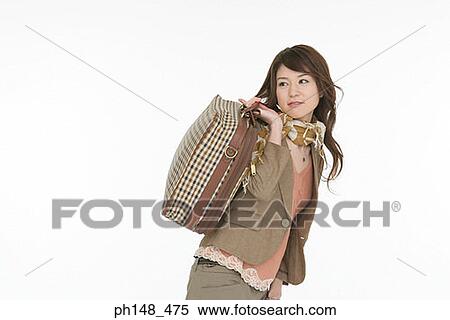 Stock Photography - Side profile of a young woman carrying a suitcase over her shoulder. Fotosearch