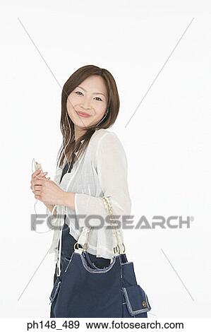 Stock Photo - Side profile of a young woman listening to an MP3 player. Fotosearch