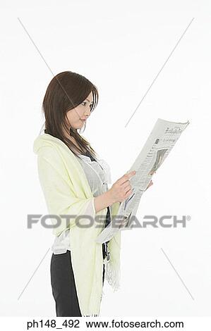 Stock Image - Side profile of a young woman reading a newspaper. Fotosearch