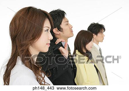 Stock Image - Side profile of two businesswomen and two businessmen in a row. Fotosearch