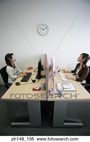 Side profile of two businesswomen wearing headsets and looking at a clock on the wall View Large Photo Image Stock Photograph - Side profile of two businesswomen wearing headsets and looking at a clock on the wall. Fotosearch