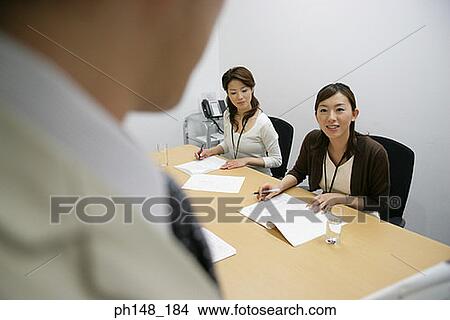 Picture - Two businesswomen and a businessman in a meeting. Fotosearch