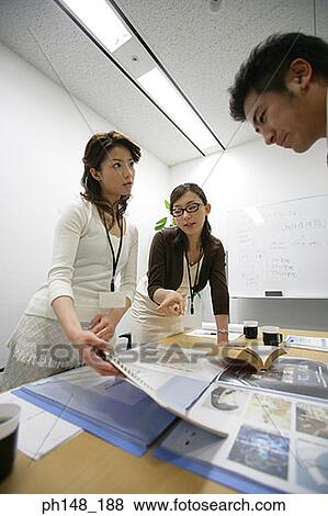 Two businesswomen and a businessman discussing documents in a conference room View Large Photo Image Stock Photo - Two businesswomen and a businessman discussing documents in a conference room. Fotosearch