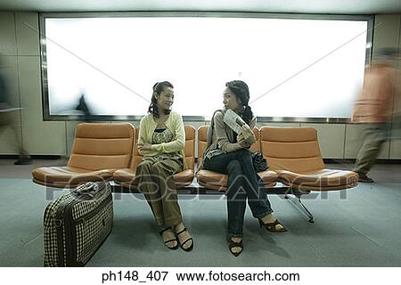 Two young women sitting on chairs and looking at each other View Large Photo Image Stock Photo - Two young women sitting on chairs and looking at each other. Fotosearch