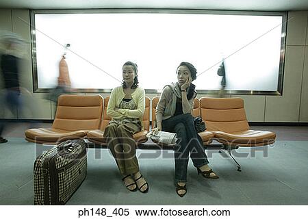 Stock Photography - Two young women sitting on chairs and waiting. Fotosearch
