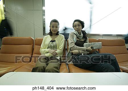Picture - Two young women sitting on chairs. Fotosearch