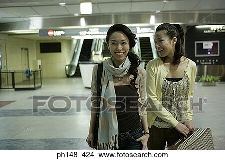 Two young women smiling at a subway station View Large Photo Image Picture - Two young women smiling at a subway station. Fotosearch