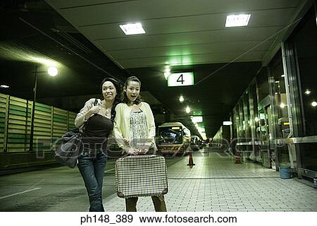 Stock Photo - Two young women smiling at a subway station. Fotosearch