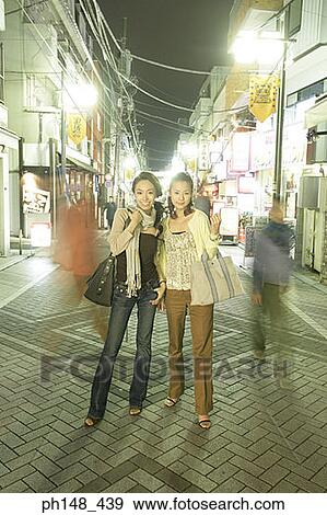 Two young women standing on the street and smiling View Large Photo Image Stock Photo - Two young women standing on the street and smiling. Fotosearch