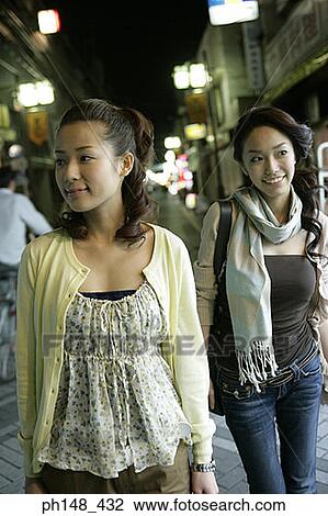 Two young women walking and smiling on the street View Large Photo Image Stock Image - Two young women walking and smiling on the street. Fotosearch