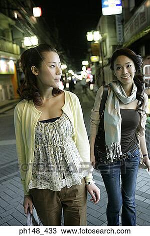 Two young women walking and smiling on the street View Large Photo Image Stock Image - Two young women walking and smiling on the street. Fotosearch