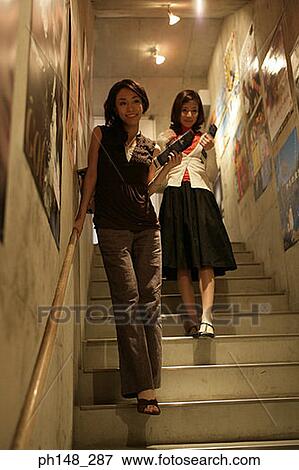Stock Photo - Two young women walking down stairs. Fotosearch