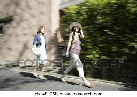 Two young women walking on the road View Large Photo Image Stock Photo - Two young women walking on the road. Fotosearch