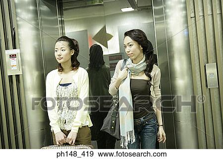 Two young women walking out of an elevator with luggage View Large Photo Image Stock Photo - Two young women walking out of an elevator with luggage. Fotosearch