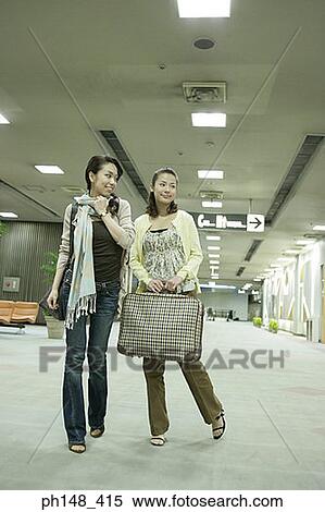 Stock Photography - Two young women with luggage at a subway station. Fotosearch
