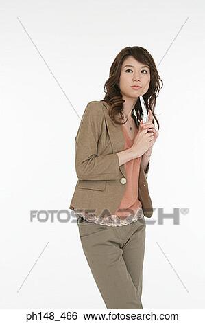 Stock Photograph - Young woman holding a mobile phone and thinking. Fotosearch