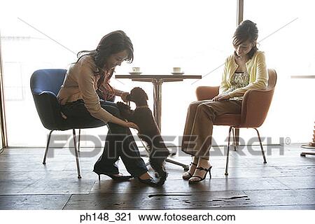 Young woman holding a puppy with another woman sitting beside her View Large Photo Image Stock Image - Young woman holding a puppy with another woman sitting beside her. Fotosearch