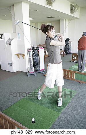 Young woman playing golf with a mature man playing in the background View Large Photo Image Stock Photo - Young woman playing golf with a mature man playing in the background. Fotosearch