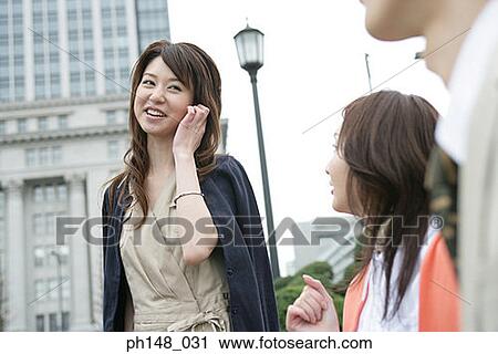 Young woman smiling with another young woman looking at her View Large Photo Image Stock Image - Young woman smiling with another young woman looking at her. Fotosearch