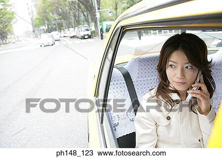 Young woman using a mobile phone in a car View Large Photo Image Stock Image - Young woman using a mobile phone in a car. Fotosearch