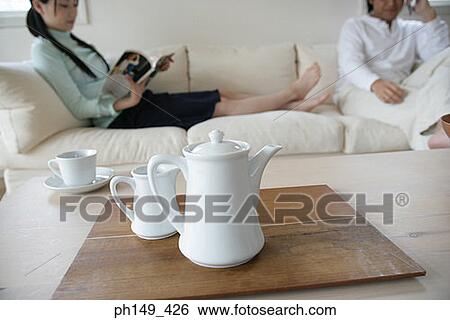 Close-up of a tea kettle on the table with a young couple sitting on a couch in the background View Large Photo Image Stock Photograph - Close-up of a tea kettle on the table with a young couple sitting on a couch in the background. Fotosearch
