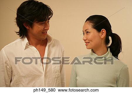 Close-up of a young couple looking at each other and smiling View Large Photo Image Stock Image - Close-up of a young couple looking at each other and smiling. Fotosearch