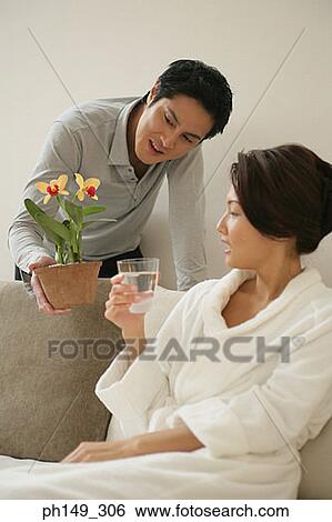 Close-up of a young man giving a potted plant to a young woman View Large Photo Image Stock Photograph - Close-up of a young man giving a potted plant to a young woman. Fotosearch
