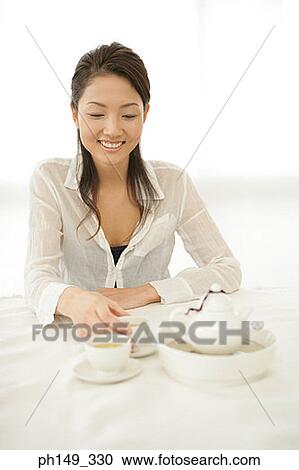Close-up of a young woman holding a cup of tea and smiling View Large Photo Image Stock Image - Close-up of a young woman holding a cup of tea and smiling. Fotosearch