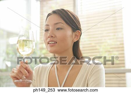 Close-up of a young woman holding a glass of white wine View Large Photo Image Stock Image - Close-up of a young woman holding a glass of white wine. Fotosearch