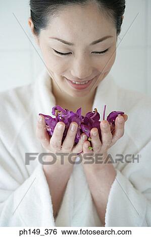 Close-up of a young woman holding a handful of flowers and smiling View Large Photo Image Stock Photograph - Close-up of a young woman holding a handful of flowers and smiling. Fotosearch