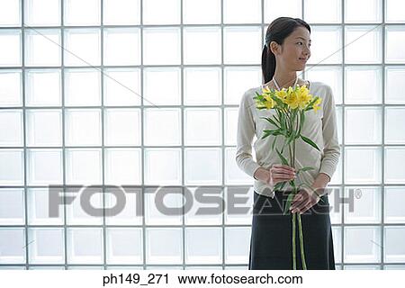 Stock Image - Close-up of a young woman holding flowers. Fotosearch