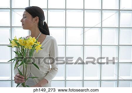 Close-up of a young woman holding flowers View Large Photo Image Stock Image - Close-up of a young woman holding flowers. Fotosearch