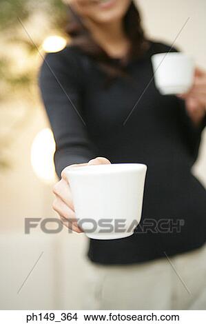 Close-up of a young woman holding two coffee cups View Large Photo Image Picture - Close-up of a young woman holding two coffee cups. Fotosearch
