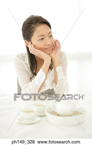 Close-up of a young woman smiling at the table View Large Photo Image Stock Photo - Close-up of a young woman smiling at the table. Fotosearch