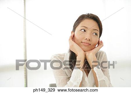 Close-up of a young woman with her hands on her chin View Large Photo Image Stock Photo - Close-up of a young woman with her hands on her chin. Fotosearch