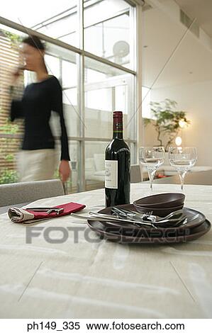 Close-up of crockery and a wine bottle in a table with a woman in the background View Large Photo Image Stock Photography - Close-up of crockery and a wine bottle in a table with a woman in the background. Fotosearch